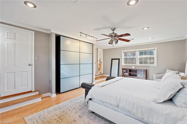 bedroom featuring crown molding, track lighting, and light hardwood / wood-style floors