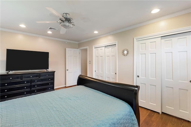 bedroom featuring multiple closets, ceiling fan, dark hardwood / wood-style flooring, and crown molding