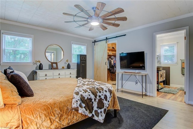 3412 Smithtown Rd, East Bend, NC 27018 - bedroom with wood finished floors, a barn door, a walk in closet, crown molding, and ceiling fan