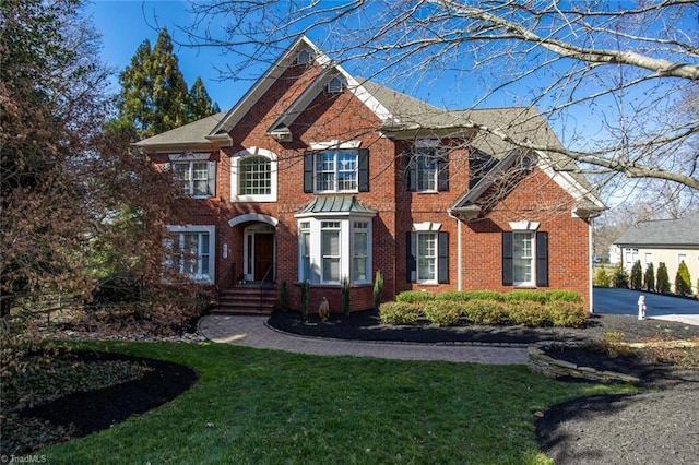 georgian-style home featuring a front lawn and brick siding