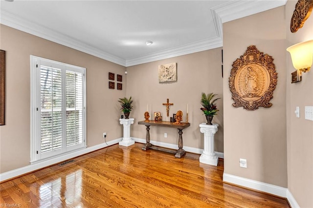 interior space featuring ornamental molding, visible vents, baseboards, and wood finished floors