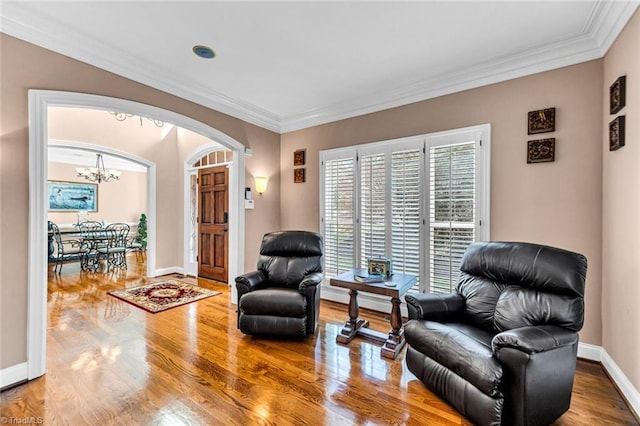 sitting room featuring baseboards, crown molding, arched walkways, and wood finished floors