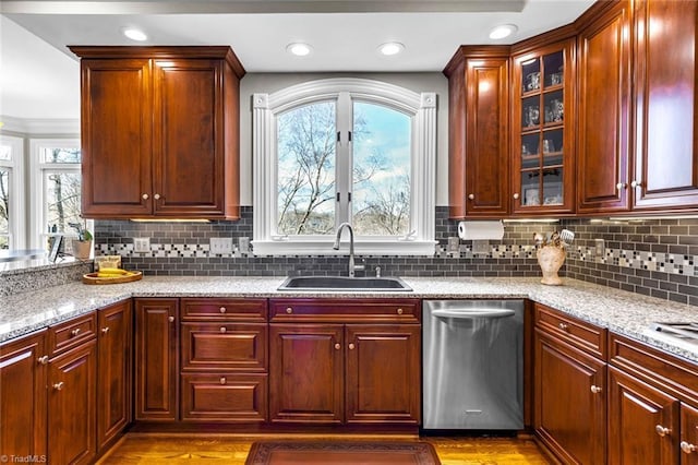 kitchen featuring light stone counters, a wealth of natural light, dishwasher, and a sink