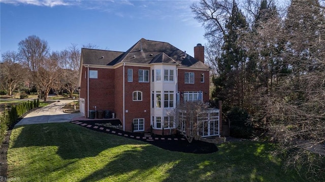 view of side of property featuring brick siding, a yard, a chimney, and central air condition unit