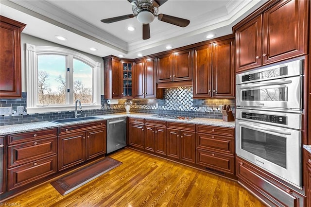 kitchen with decorative backsplash, appliances with stainless steel finishes, dark wood-type flooring, a sink, and light stone countertops