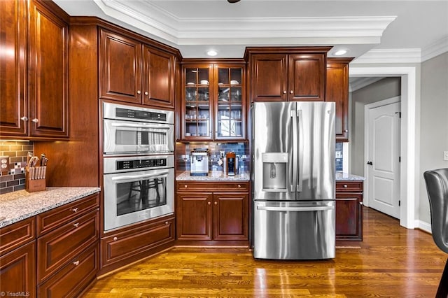 kitchen with dark wood-style floors, stainless steel appliances, glass insert cabinets, and light stone countertops