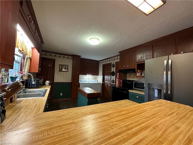 kitchen featuring appliances with stainless steel finishes, wood counters, separate washer and dryer, sink, and kitchen peninsula