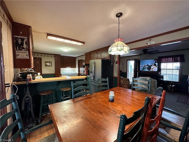 dining area with hardwood / wood-style floors, ornamental molding, a textured ceiling, and ceiling fan