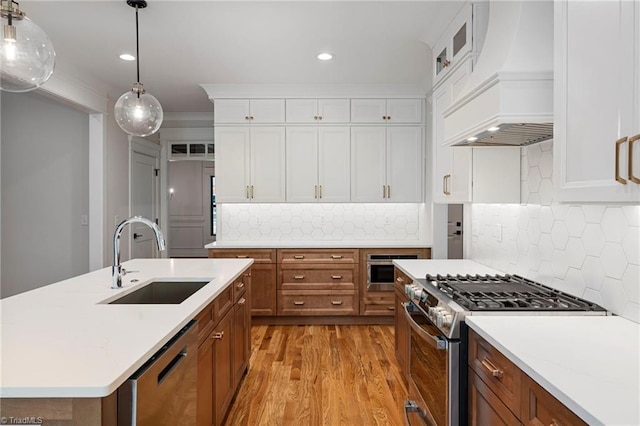 kitchen featuring premium range hood, sink, appliances with stainless steel finishes, a kitchen island with sink, and backsplash