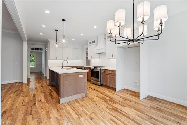 kitchen featuring sink, stainless steel gas range, white cabinets, a center island with sink, and custom exhaust hood