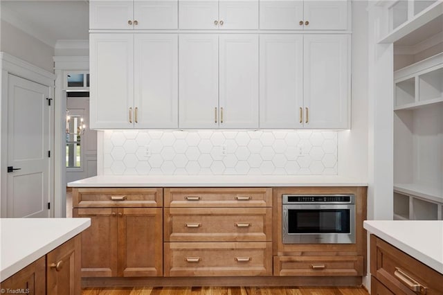 kitchen with white cabinets, oven, backsplash, and light hardwood / wood-style floors