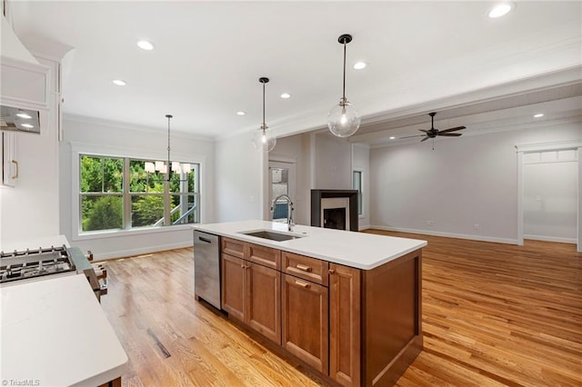 kitchen with pendant lighting, stainless steel dishwasher, sink, and a kitchen island with sink