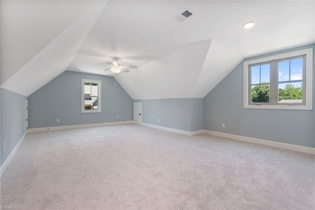 additional living space featuring light carpet, vaulted ceiling, and a healthy amount of sunlight