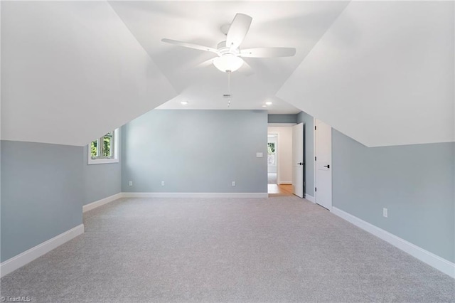 additional living space featuring vaulted ceiling, light colored carpet, and ceiling fan