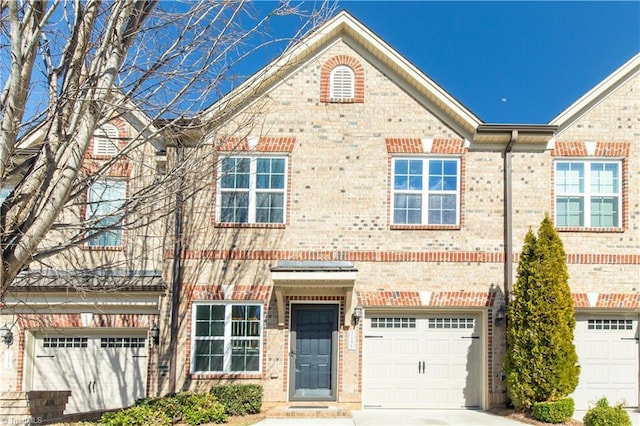 townhome / multi-family property with a garage, concrete driveway, and brick siding