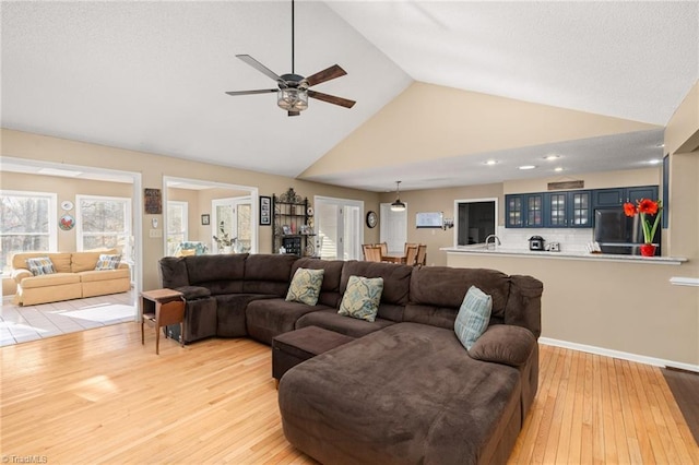 living room with light wood-type flooring and high vaulted ceiling