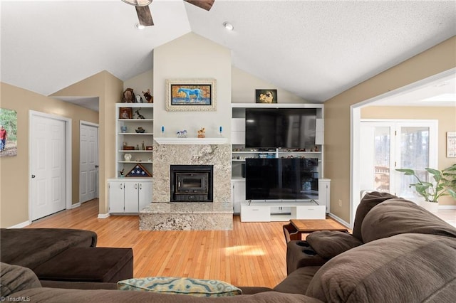 living area with baseboards, vaulted ceiling, a fireplace, wood finished floors, and a textured ceiling