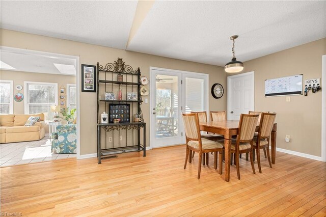 dining space with a wealth of natural light, baseboards, light wood-style floors, and a textured ceiling