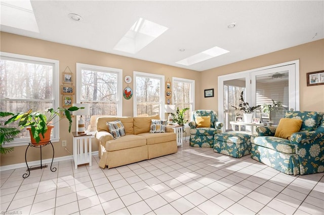 living room with a skylight, light tile patterned floors, and baseboards