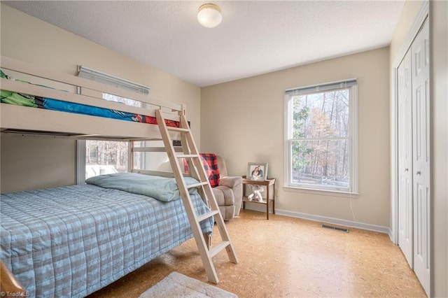 bedroom with baseboards, multiple windows, a textured ceiling, and a closet