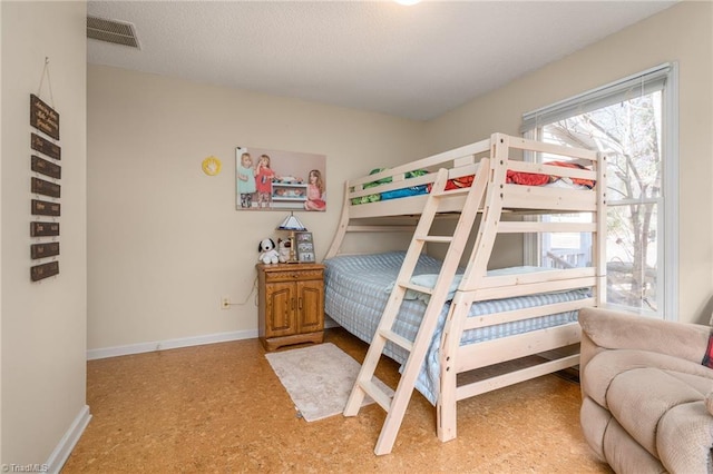 bedroom with visible vents, a textured ceiling, and baseboards