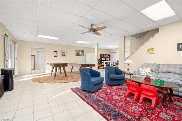 living area with light tile patterned floors, a paneled ceiling, and ceiling fan