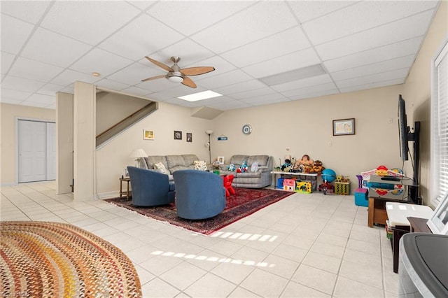 living area featuring light tile patterned floors, a paneled ceiling, and a ceiling fan