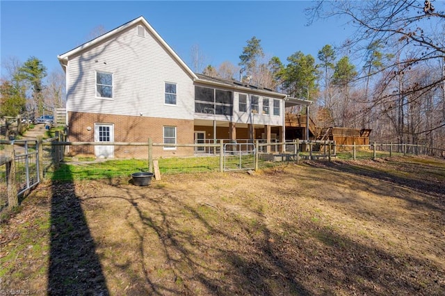 back of property featuring stairway, brick siding, a fenced backyard, and a lawn