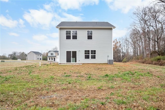 rear view of property with a lawn and central air condition unit