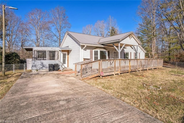 view of front of house with a front yard, a sunroom, driveway, and fence