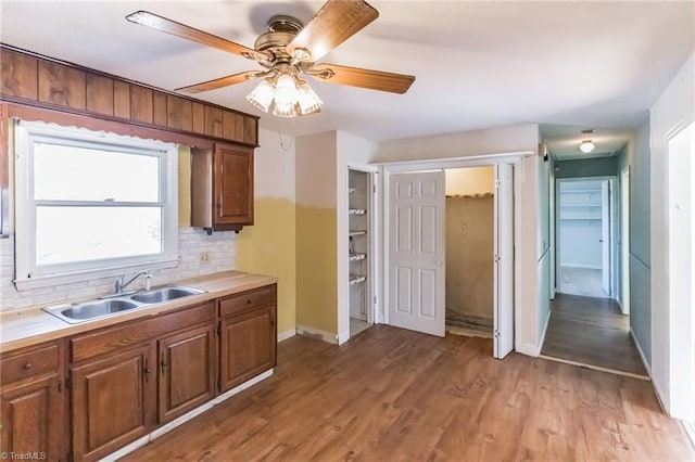 kitchen with light countertops, a sink, light wood finished floors, and decorative backsplash