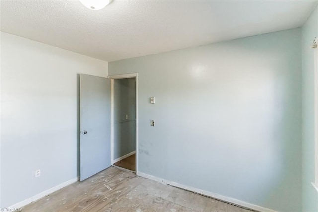 unfurnished room with baseboards and a textured ceiling