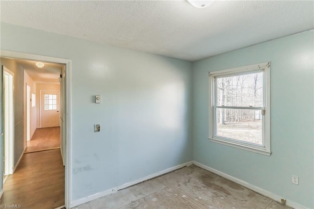 empty room with a textured ceiling and baseboards