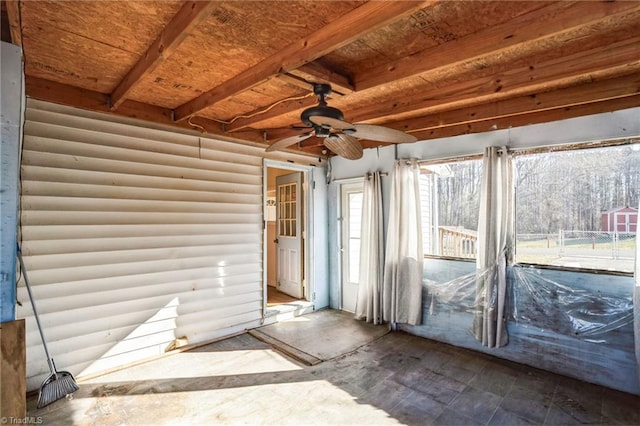 unfurnished sunroom featuring a ceiling fan and beamed ceiling