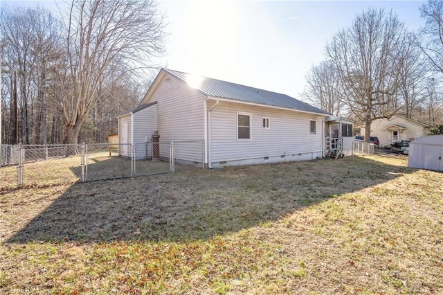 rear view of house featuring a lawn, crawl space, metal roof, fence, and an outdoor structure