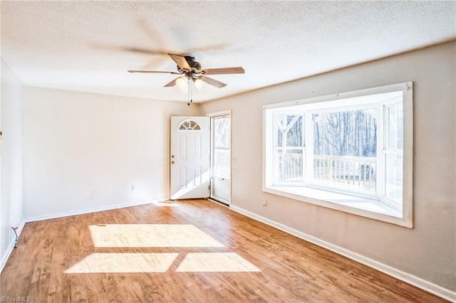 unfurnished room with a ceiling fan, a textured ceiling, baseboards, and wood finished floors