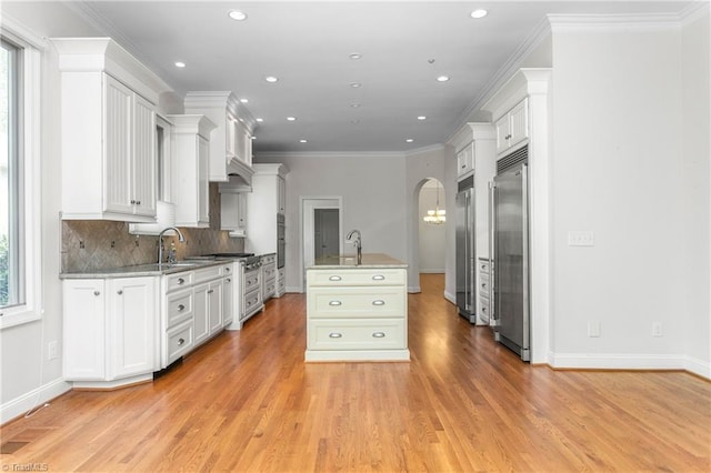 kitchen with decorative backsplash, stainless steel built in refrigerator, a healthy amount of sunlight, and light wood-style flooring