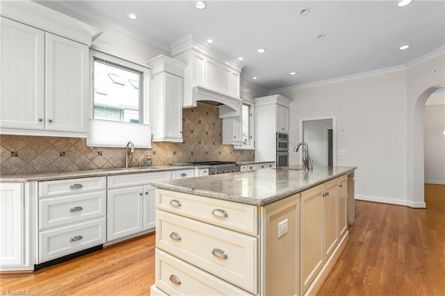 kitchen with arched walkways, backsplash, ornamental molding, and a sink
