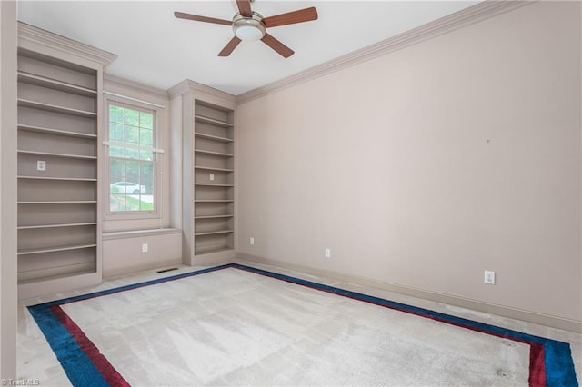 empty room with a ceiling fan, crown molding, built in shelves, baseboards, and carpet flooring