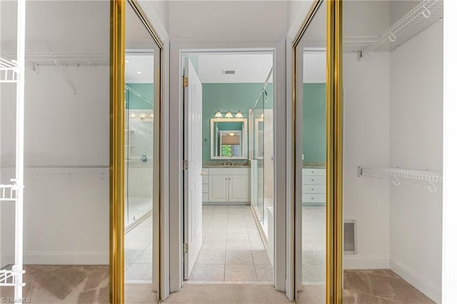 interior space featuring a walk in closet, baseboards, vanity, and visible vents