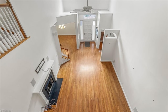 entryway with a high ceiling, a fireplace, light wood-style flooring, stairs, and ceiling fan