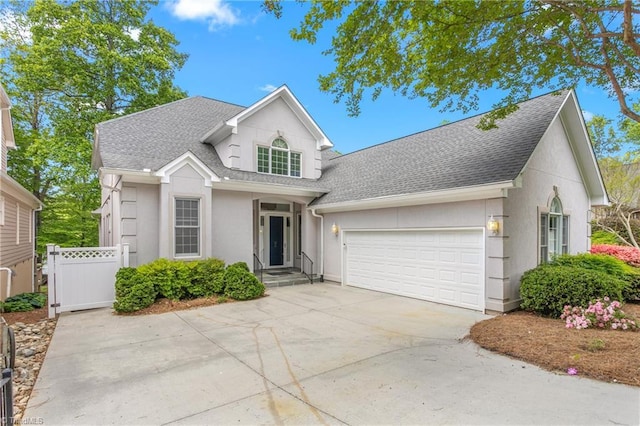 traditional home with concrete driveway, fence, a garage, stucco siding, and roof with shingles