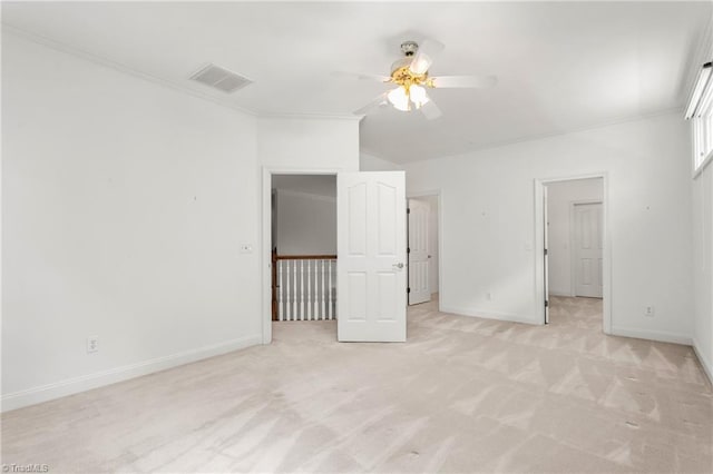 unfurnished bedroom featuring vaulted ceiling, visible vents, crown molding, baseboards, and light colored carpet