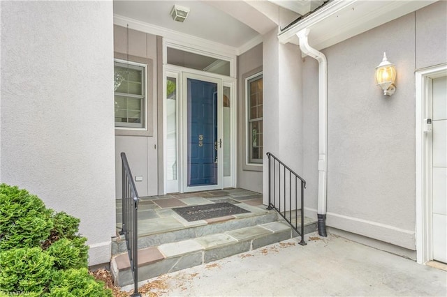 entrance to property featuring visible vents and stucco siding