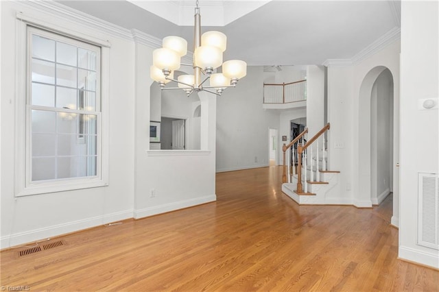 unfurnished dining area featuring a chandelier, light wood-type flooring, arched walkways, baseboards, and visible vents