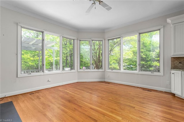 unfurnished sunroom featuring a wooden deck, baseboards, wood finished floors, and visible vents