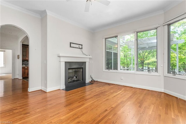 unfurnished living room featuring a fireplace with flush hearth, light wood-type flooring, arched walkways, and ceiling fan