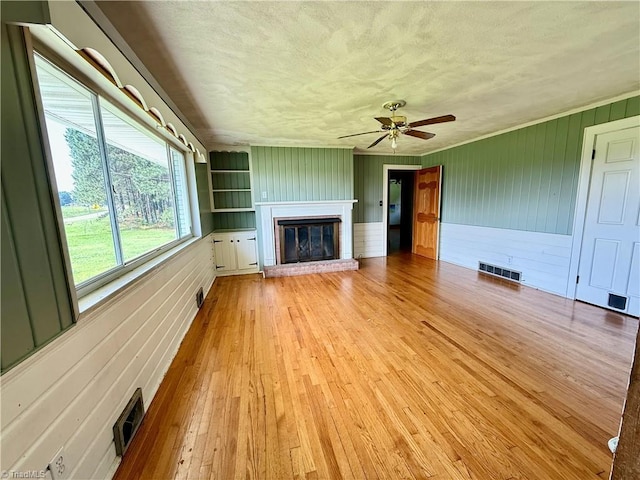 1024 Lone Hickory Rd, Yadkinville, NC 27055 - unfurnished living room featuring a brick fireplace, light wood-style floors, ceiling fan, a textured ceiling, and wooden walls