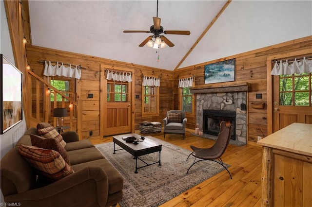 living room featuring wooden walls, plenty of natural light, high vaulted ceiling, and light wood-type flooring