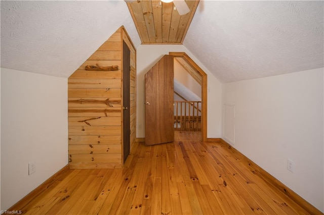 bonus room featuring vaulted ceiling, a textured ceiling, light wood finished floors, and ceiling fan